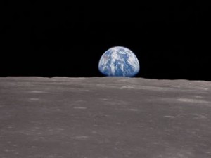 Earth rises above the horizon of the Moon before the crew of Apollo XI