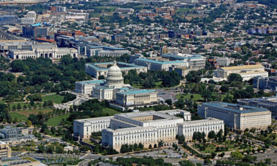 Low-altitude photograph of our nation's capital, showing the Capitol looking at the House Wing. The Botanical Gardens appear in left foreground. Note also the House and Senate office buildings.