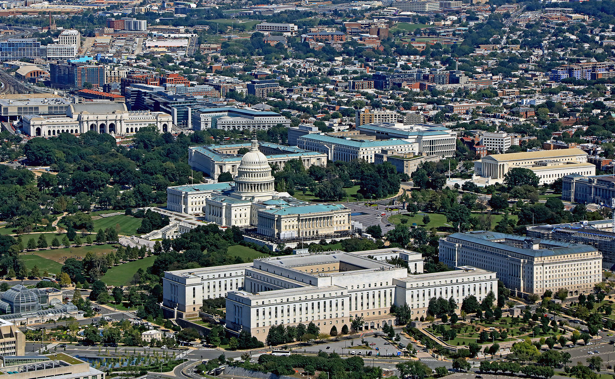 Low-altitude photograph of our nation's capital, showing the Capitol looking at the House Wing. The Botanical Gardens appear in left foreground. Note also the House and Senate office buildings.