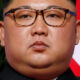 Kim Jong Un with North Korea flag background - he is on the World Watch List