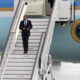 Obama crooks his arms as he skips down the boarding stairs from Air Force One