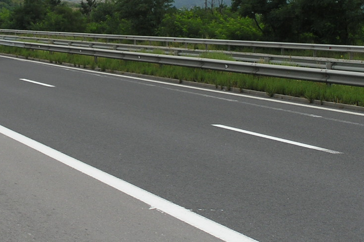 A nondescript interstate highway or similar superhighway, with median and guardrails