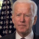 Joe Biden next to flag partially bleached in sunlight