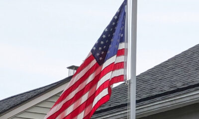 USA flag on straight pole next to a single-family house