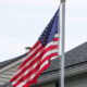 USA flag on straight pole next to a single-family house
