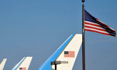 Flag of USA flies near a row of three VIP transport tails, probably C-32 757 types