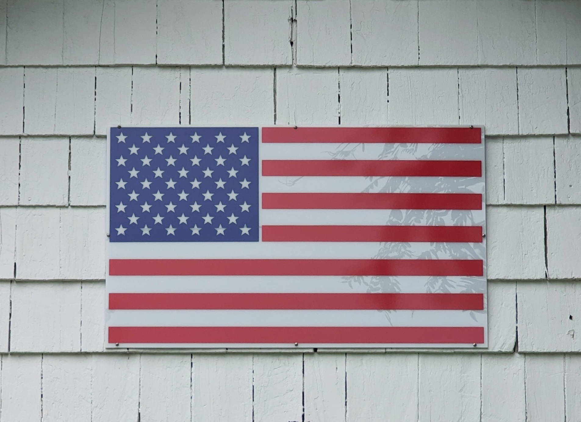Flag of USA tacked onto outside house wall made of shingles