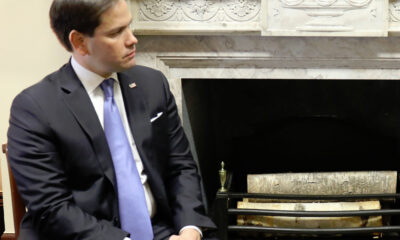 Senator Marco Rubio, R-Florida, seated next to a wood-burning open-heart fireplace with birch logs