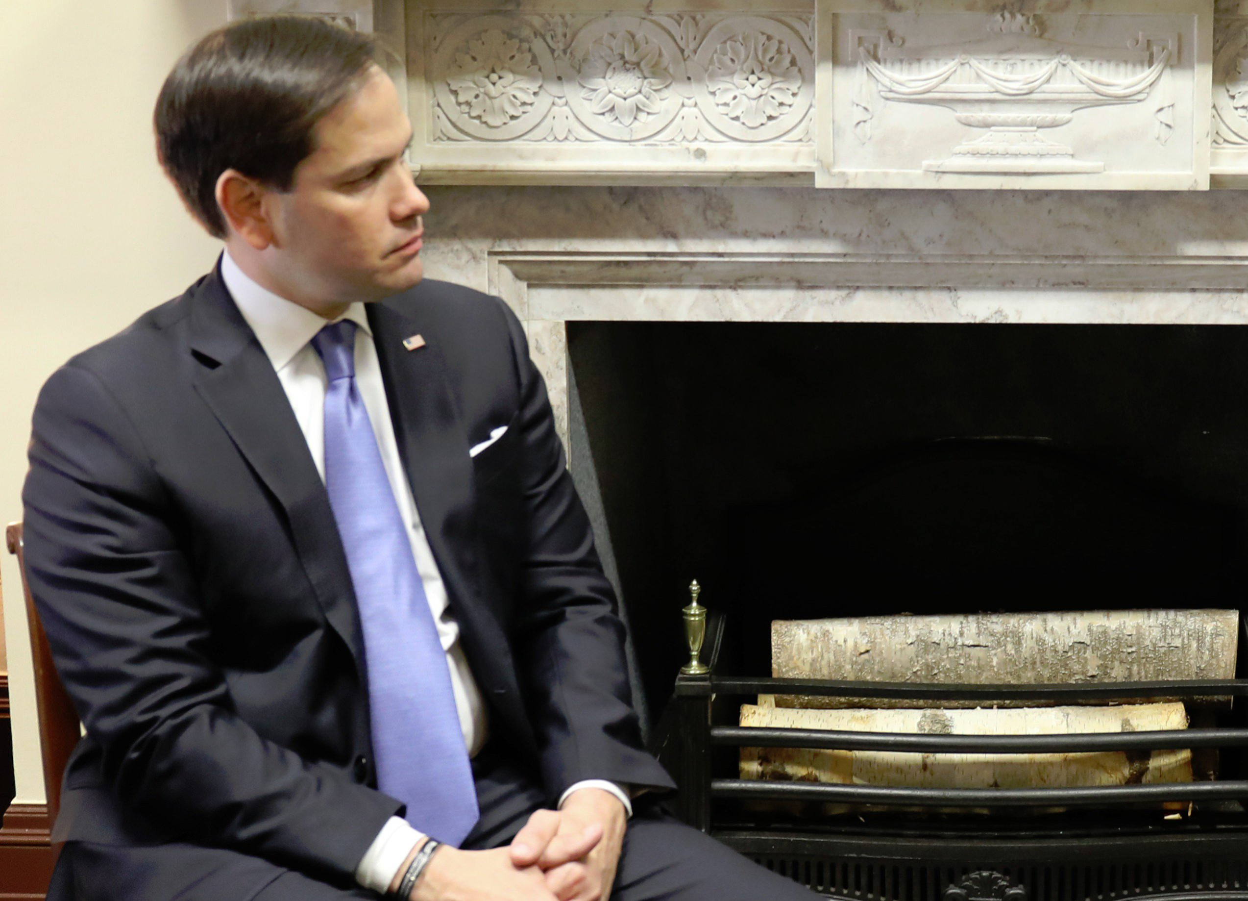 Senator Marco Rubio, R-Florida, seated next to a wood-burning open-heart fireplace with birch logs