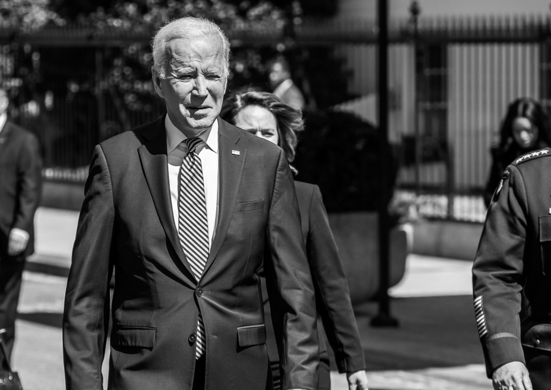 Biden in black-and-white image walking next to a general, with Vice-President Kamala Harris behind and to his left