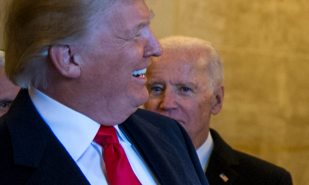 Trump, foreground, in right profile, smiles as Joe Biden, to his left, looks on with an angry frown