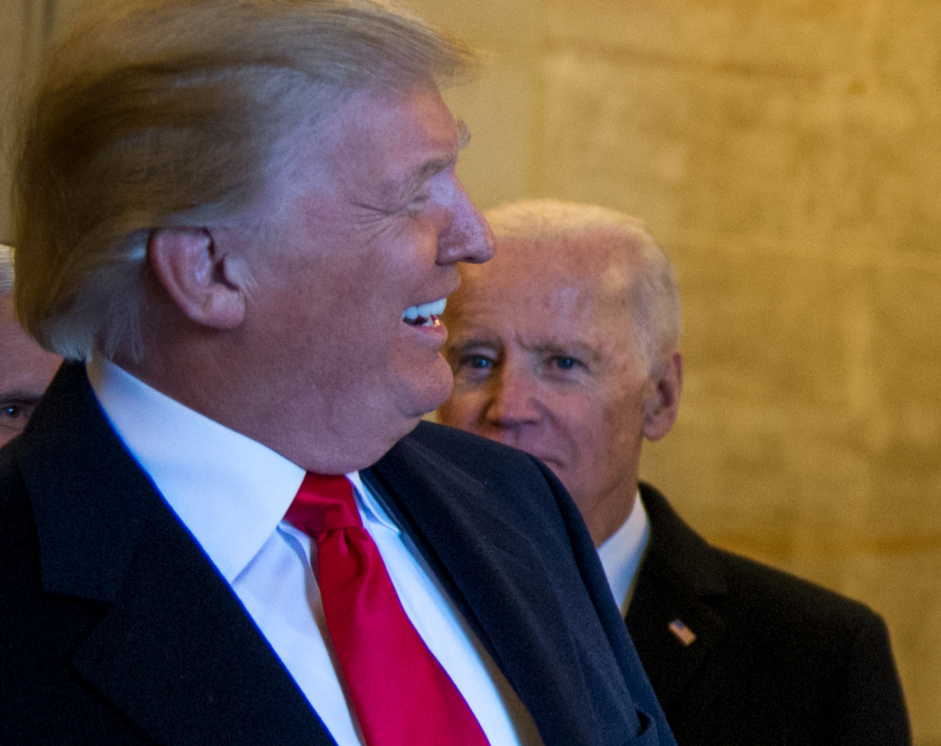 Trump, foreground, in right profile, smiles as Joe Biden, to his left, looks on with an angry frown