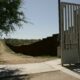 Border wall, apparently unfinished, with sidewalk and driveway in foreground