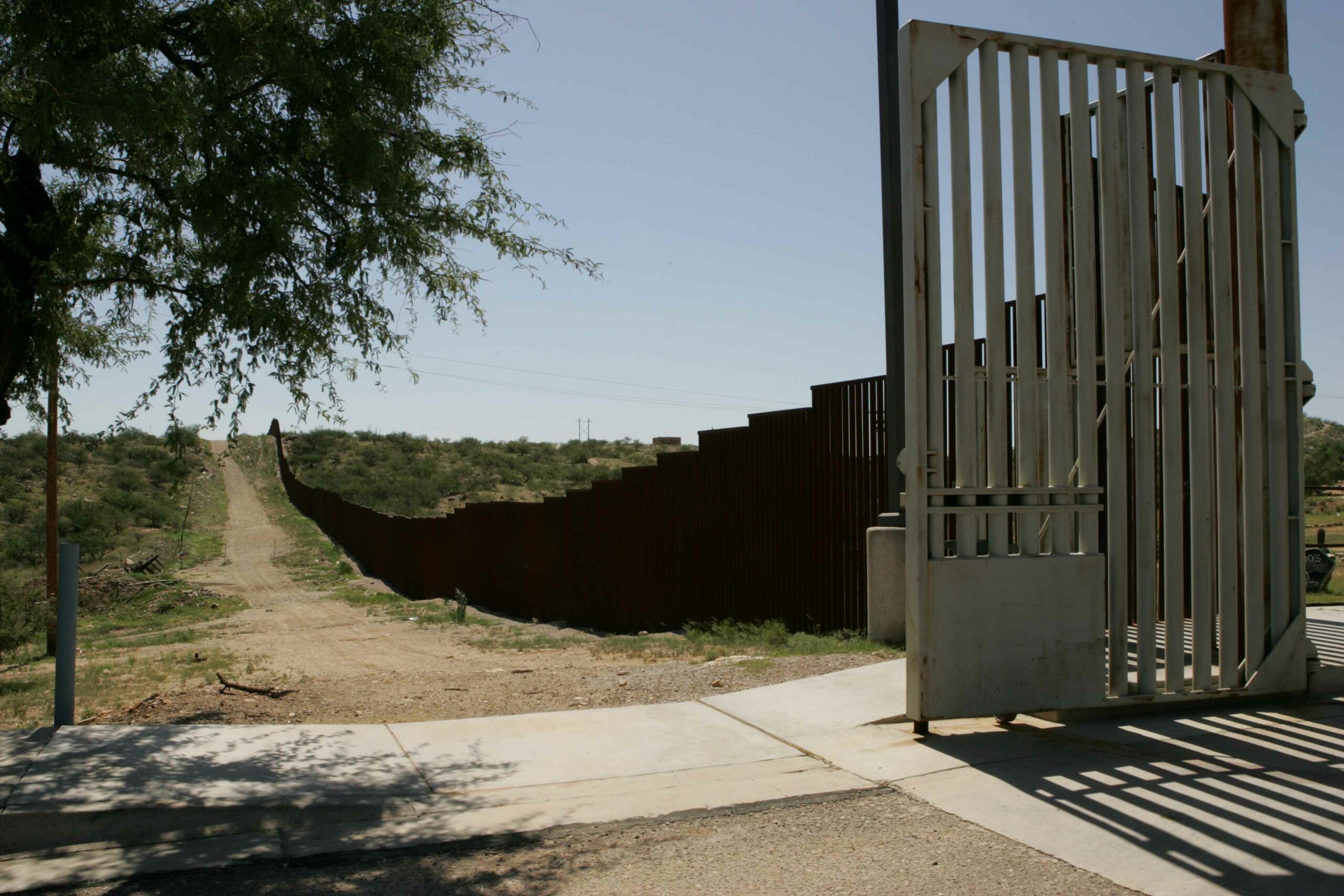 Border wall, apparently unfinished, with sidewalk and driveway in foreground