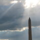 Washington Monument under clouds with sun rays shining through