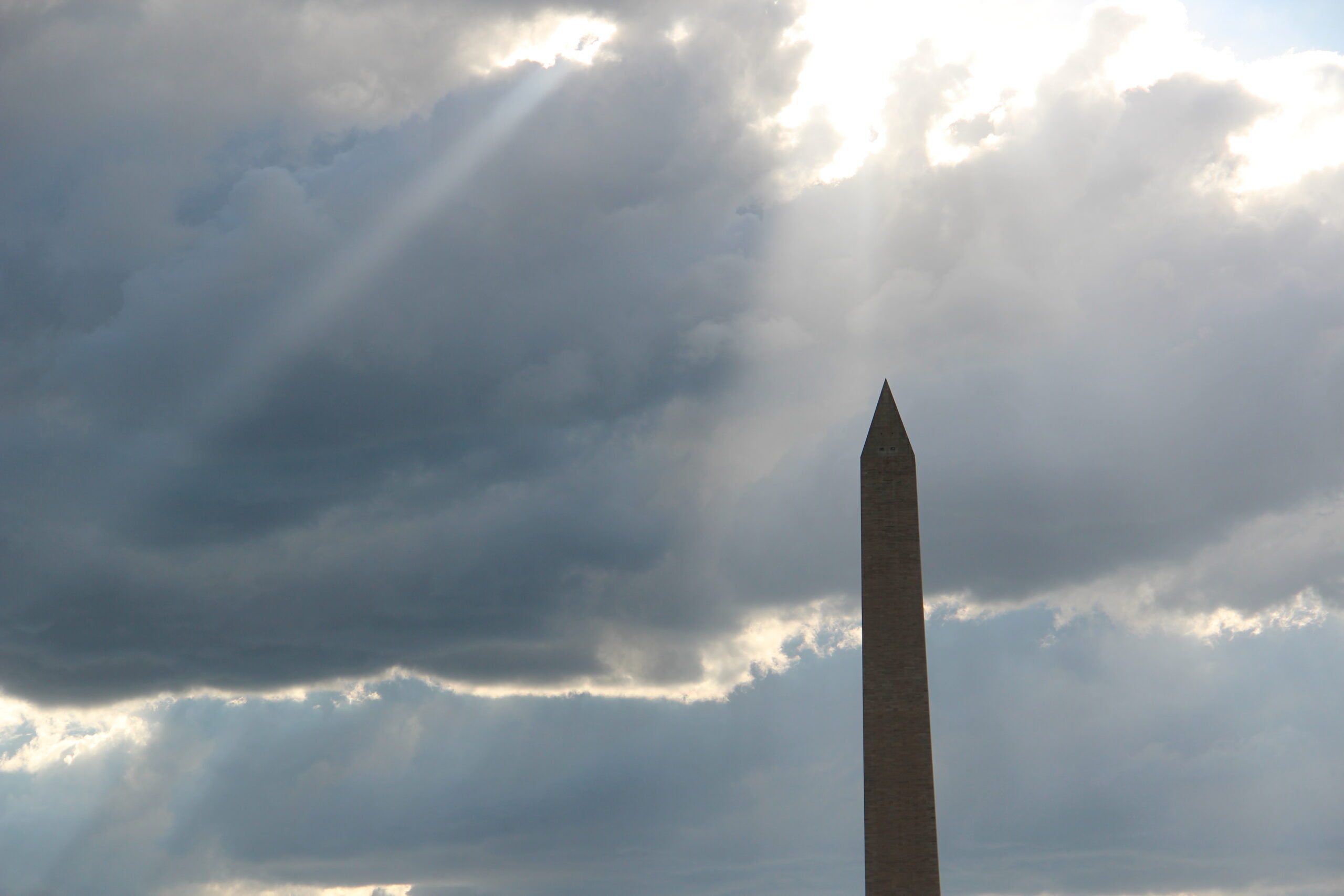 Washington Monument under clouds with sun rays shining through