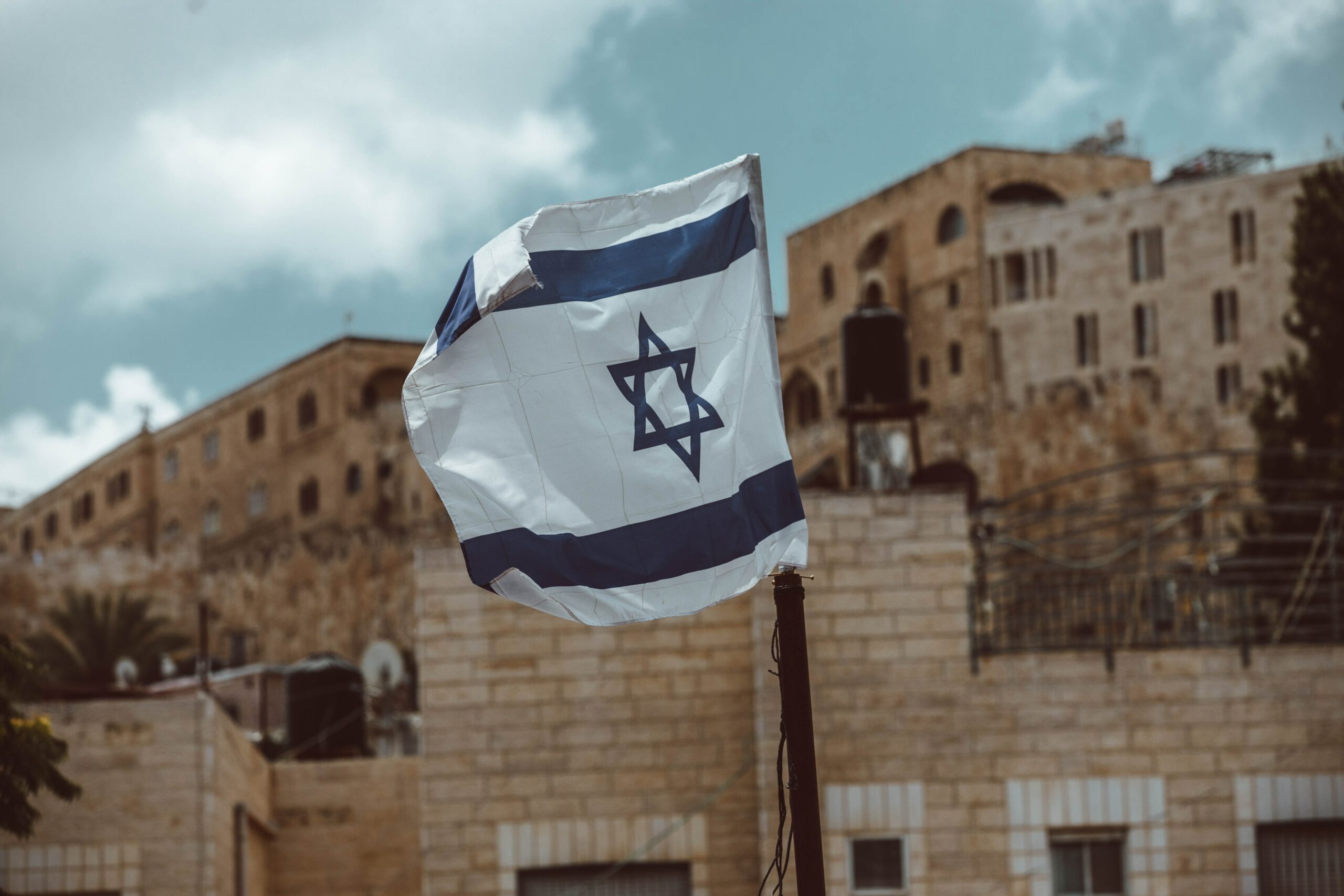 Israel flag flying near brick walls in an Israeli city (Jerusalem? Akko?)