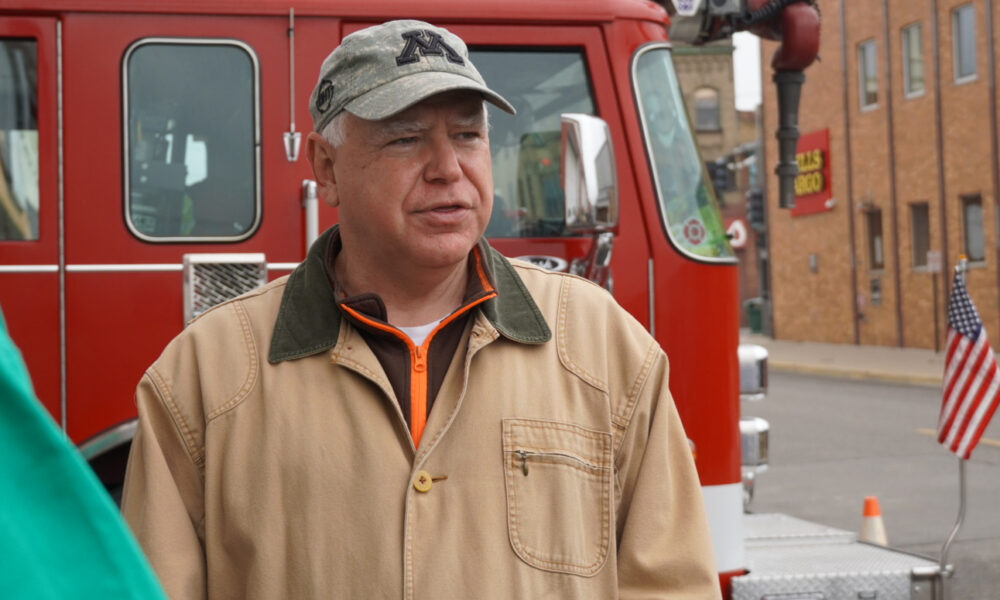 Governor Tim Walz of Minnesota next to a fire pumper with a Wells Fargo Bank branch in background