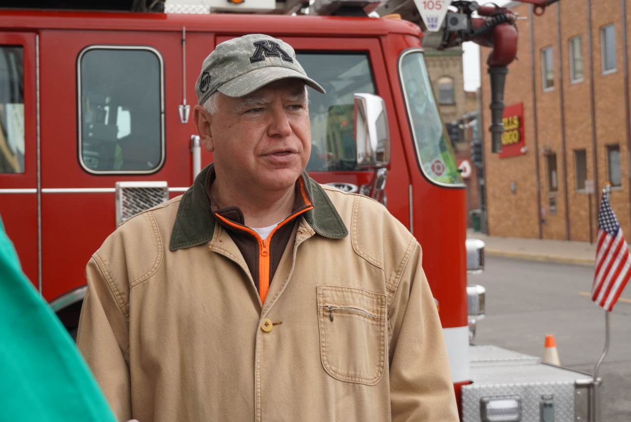 Governor Tim Walz of Minnesota next to a fire pumper with a Wells Fargo Bank branch in background