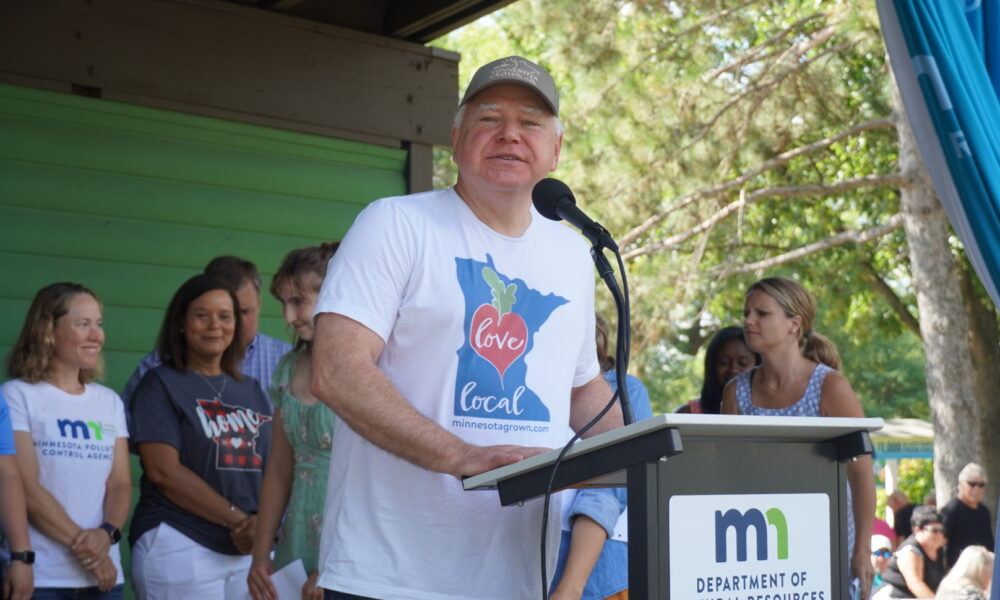 Tim Walz delivers a speech at a porch-like setting for the Minnesota Department of Natural Resources