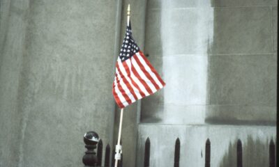 Hand-held American flag taped to a metal fence