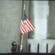 Hand-held American flag taped to a metal fence