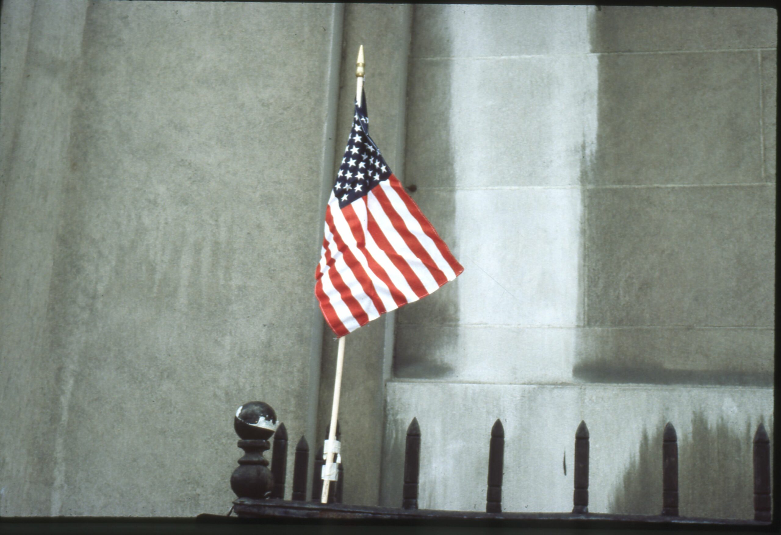 Hand-held American flag taped to a metal fence