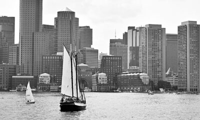 Boston skyline looking in from Boston Harbor, with wooden museum sailing vessel (USS Constitution?) in foreground