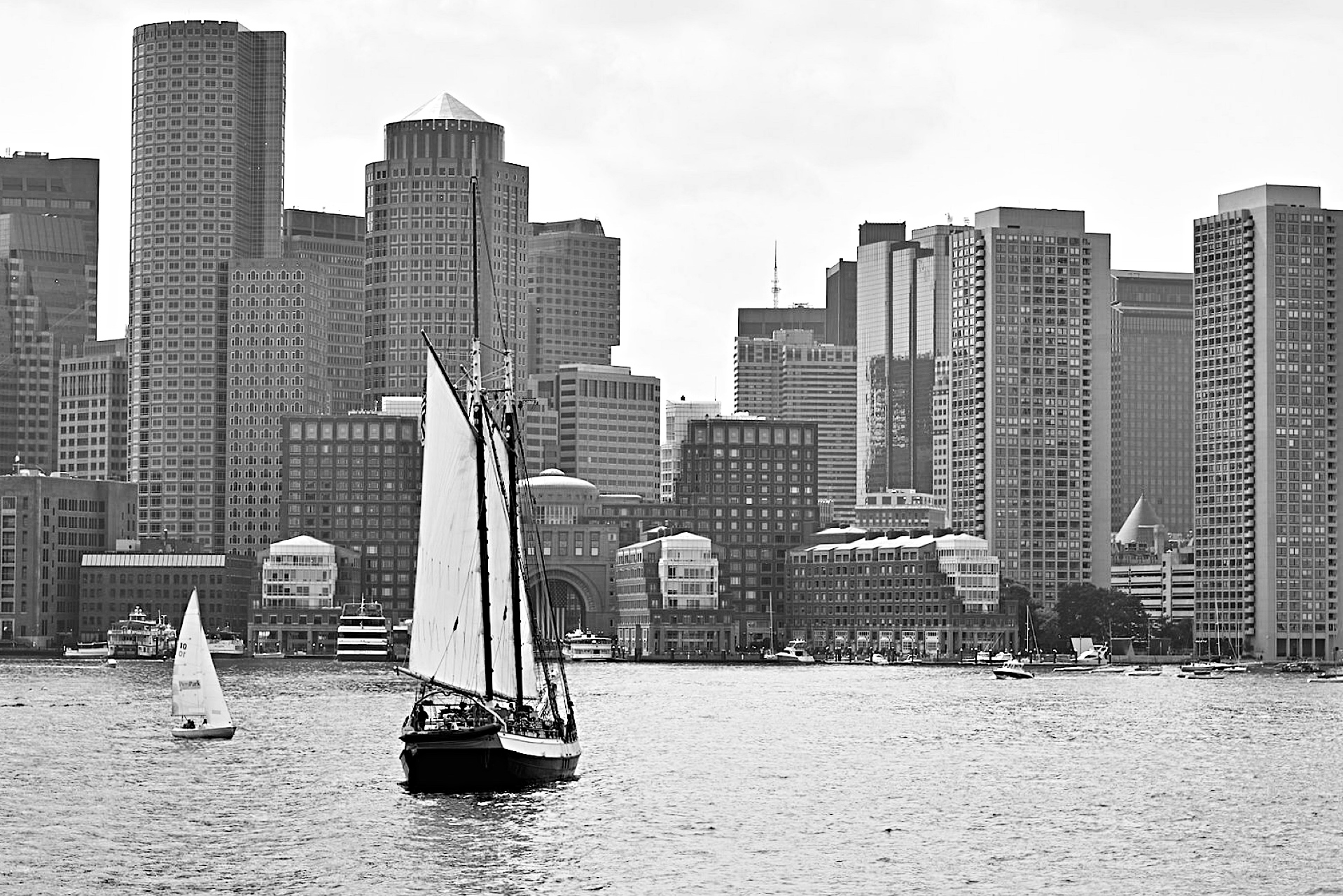 Boston skyline looking in from Boston Harbor, with wooden museum sailing vessel (USS Constitution?) in foreground