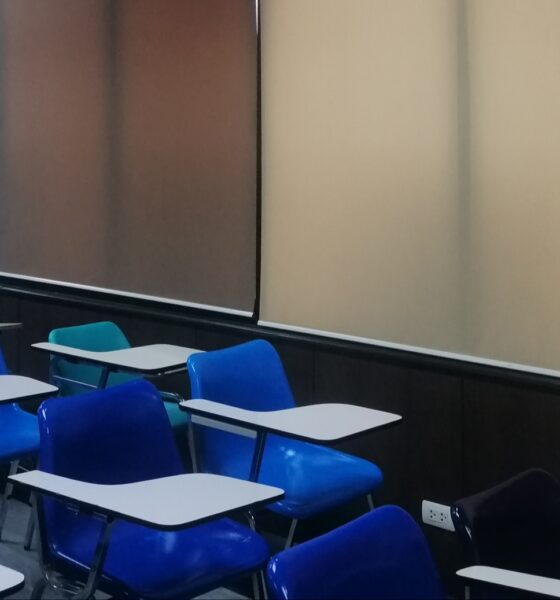 Classroom with blue chairs, multicolored marking boards, red doors, and corkboard with sheets of binary code