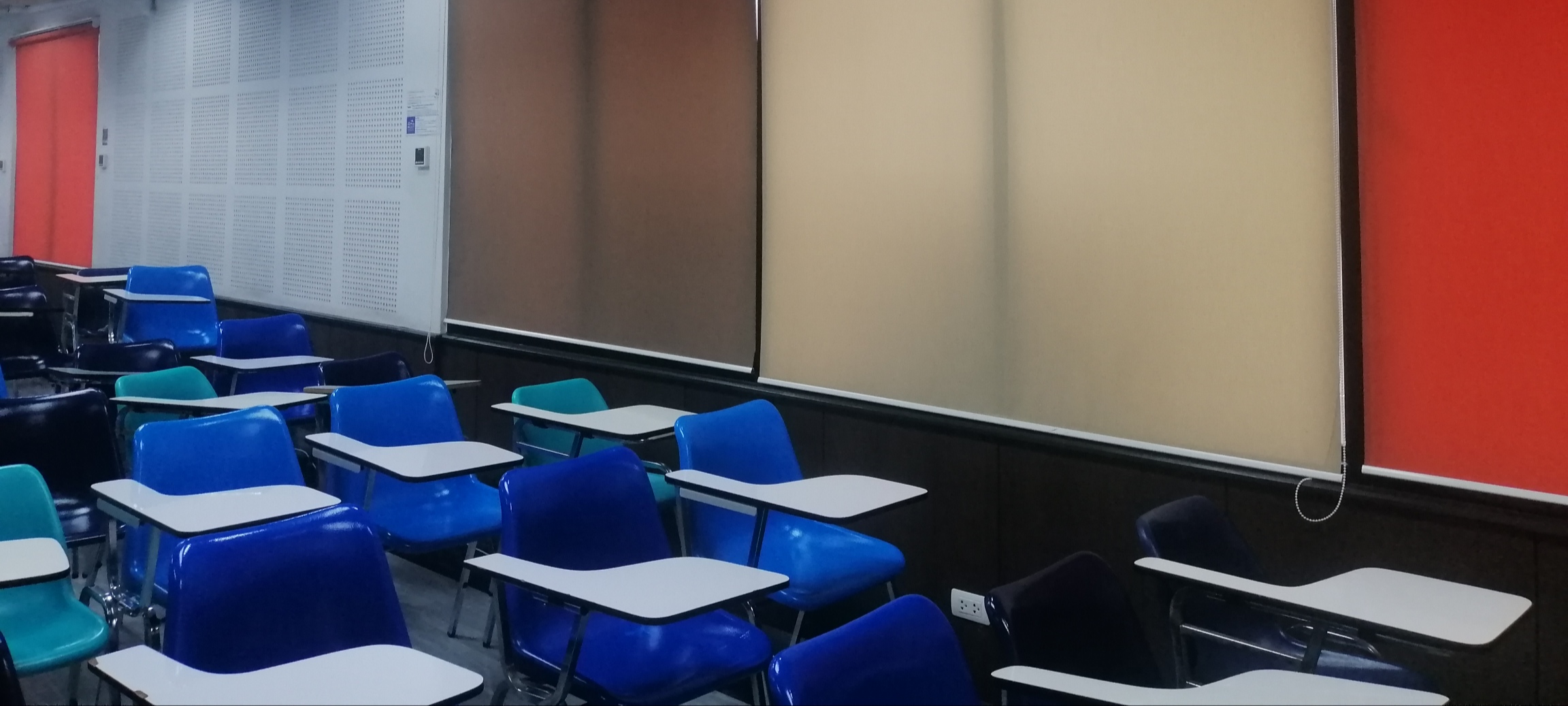 Classroom with blue chairs, multicolored marking boards, red doors, and corkboard with sheets of binary code