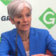 Jill Stein seated before Green Party photo-op backdrop