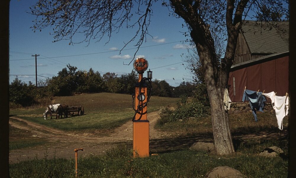 Very early-model gas pump now in a residential back yard with clothes drying on a line nearby