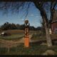 Very early-model gas pump now in a residential back yard with clothes drying on a line nearby