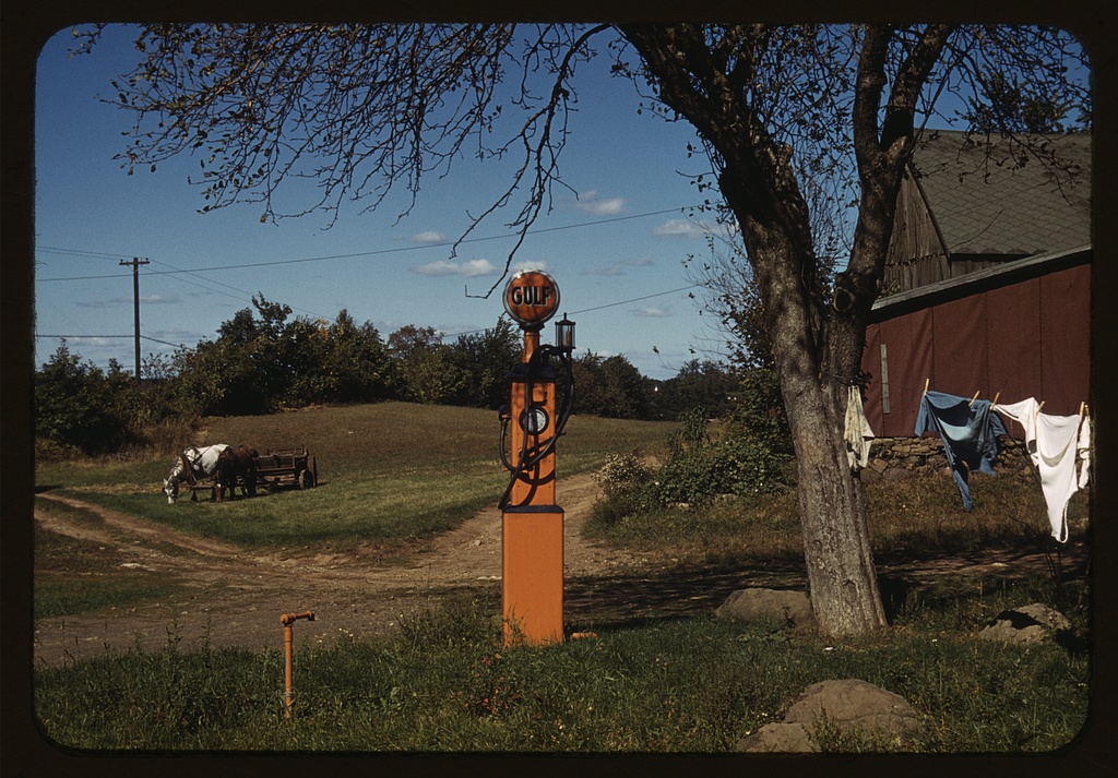 Very early-model gas pump now in a residential back yard with clothes drying on a line nearby