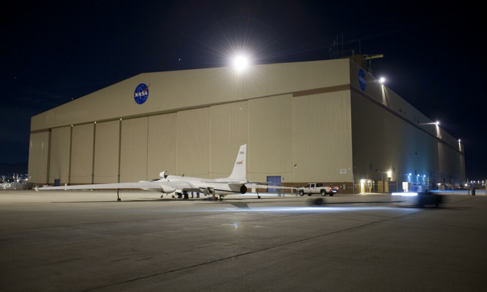 A NASA long-winged plane next to a hangar at the Palmdale Facility.