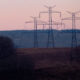 High-tension power lines dangling from their towers at sunset.