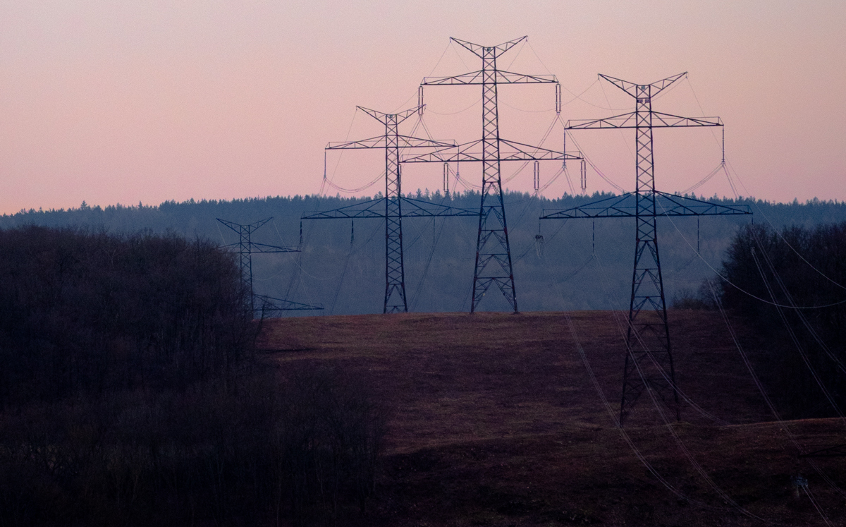 High-tension power lines dangling from their towers at sunset.