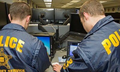 Two Secret Service agents, wearing official windbreakers, pore over computer monitors as they conduct a preliminary investigation