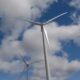 Two wind turbines in line under a partly cloudy sky