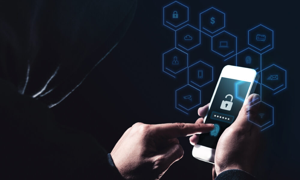 A cyber crime hacker uses a mobile phone to perpetrate another hack