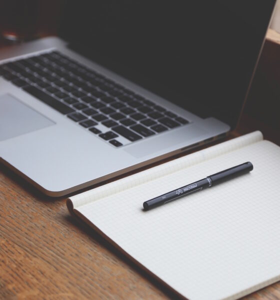 A laptop next to a notebook with gridlines and a marking pen.