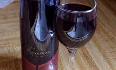 A red wine, poured from its bottle into a glass.