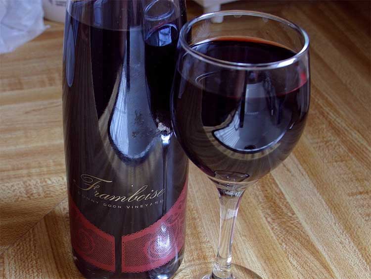A red wine, poured from its bottle into a glass.