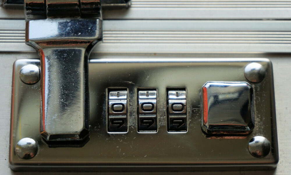 A combination lock on a suitcase, with the dials set to zero
