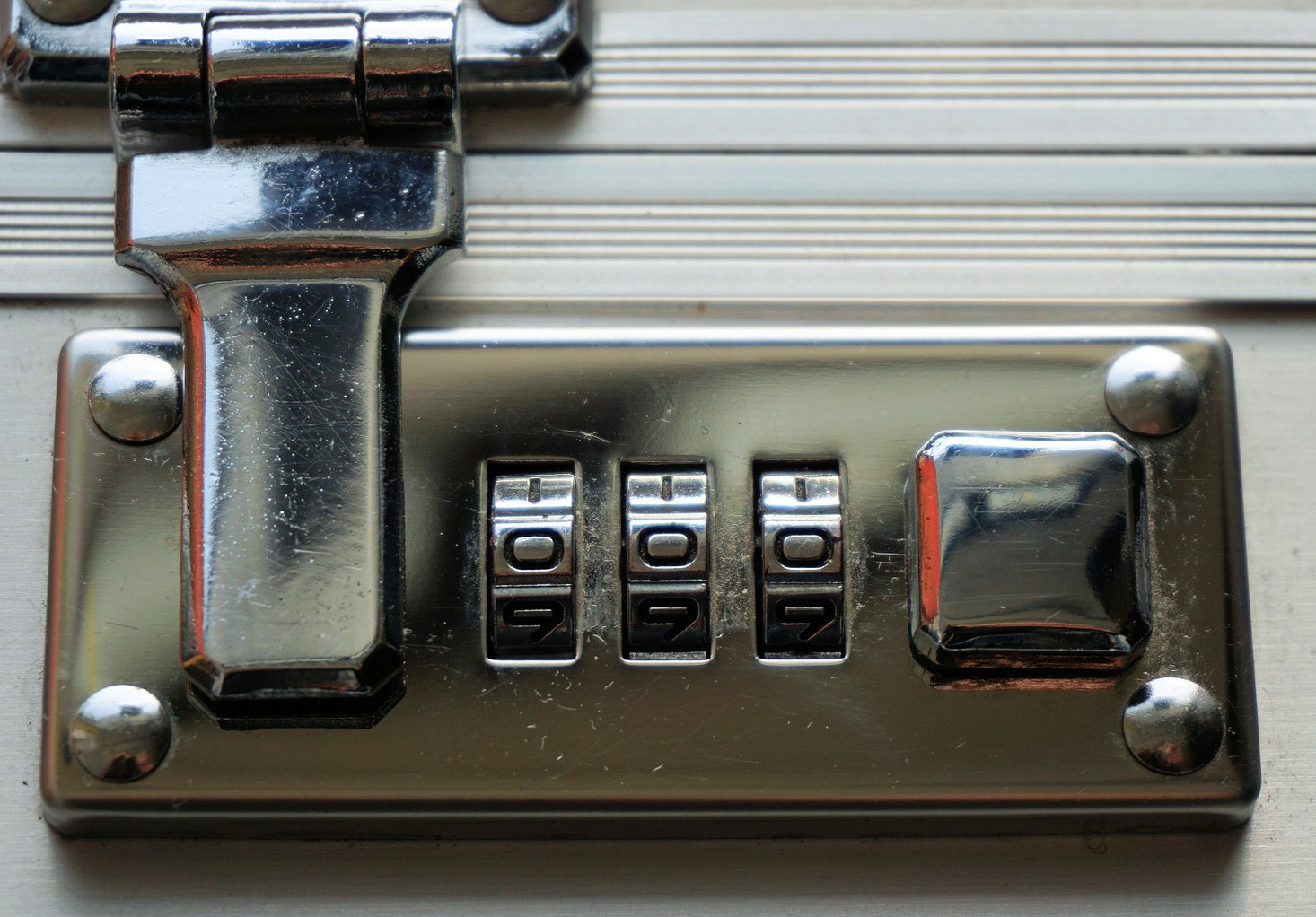 A combination lock on a suitcase, with the dials set to zero