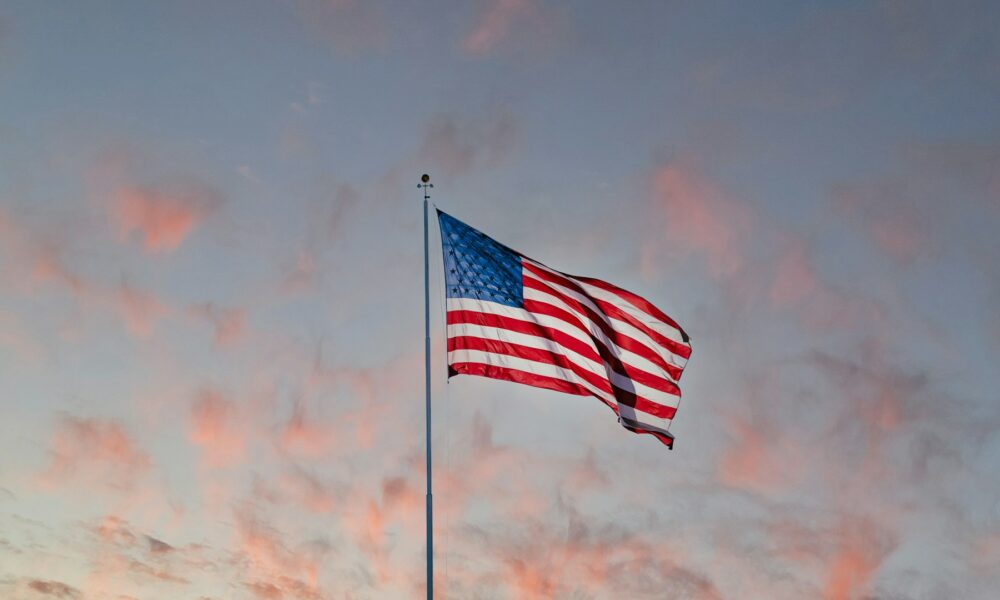 USA flag flying under partly cloudy sky at sunset