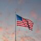 USA flag flying under partly cloudy sky at sunset
