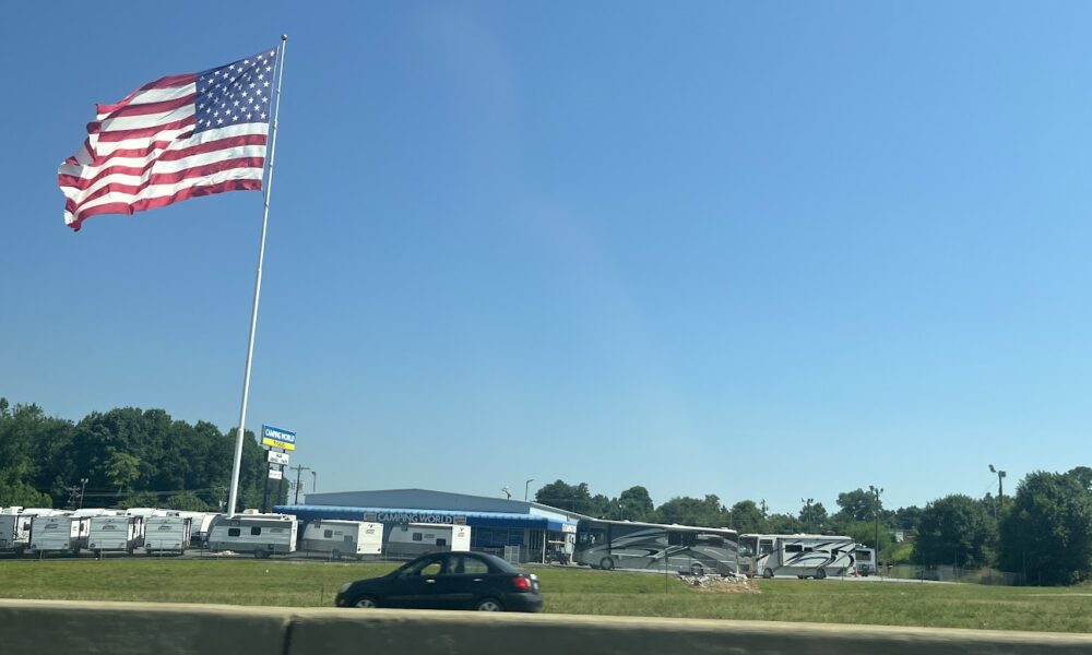 American flag flying over a camper park next to a busy highway