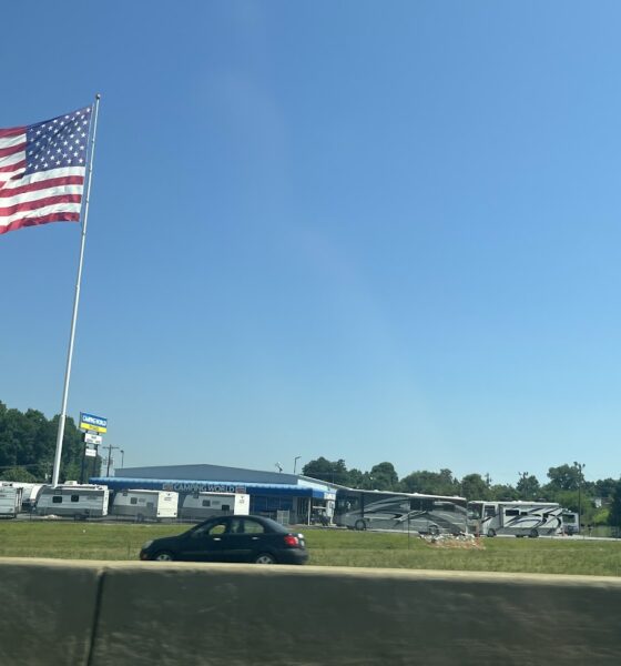 American flag flying over a camper park next to a busy highway
